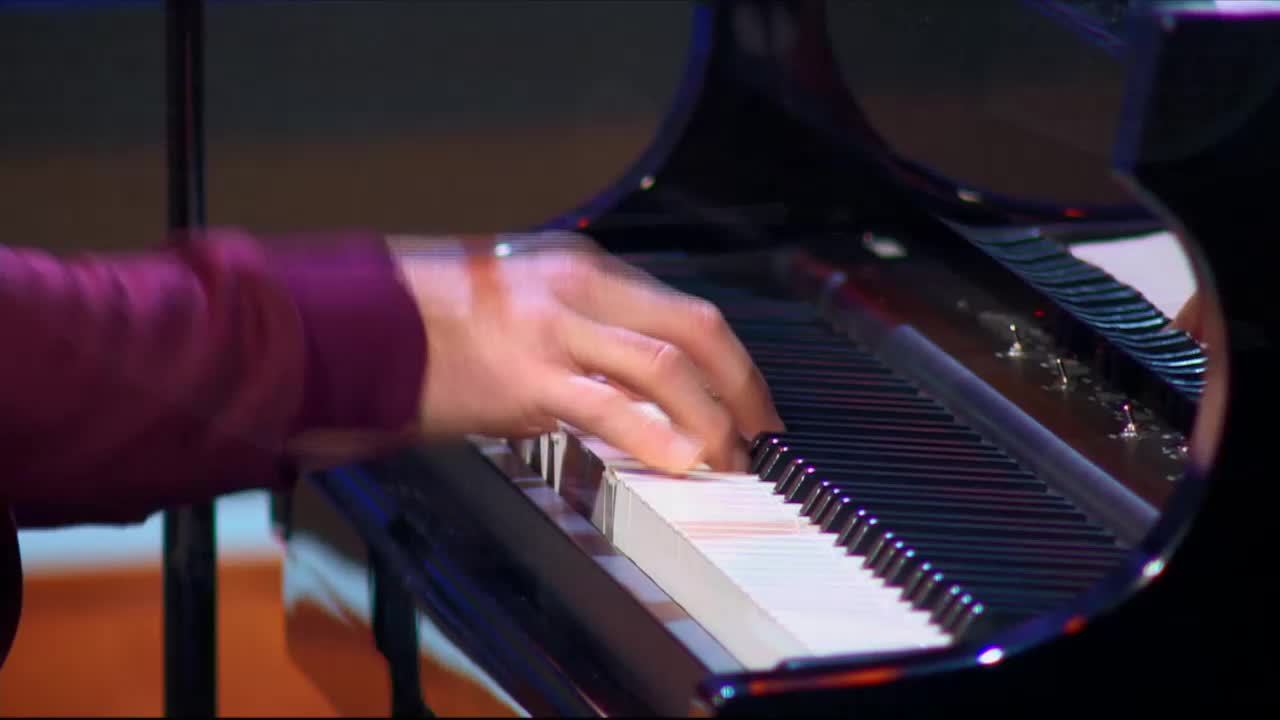 Fingers dance across the piano keys, a blur of motion against the polished black instrument. The music flows from the 3ABN Praise Him Music Network broadcast, filling the space with sound.