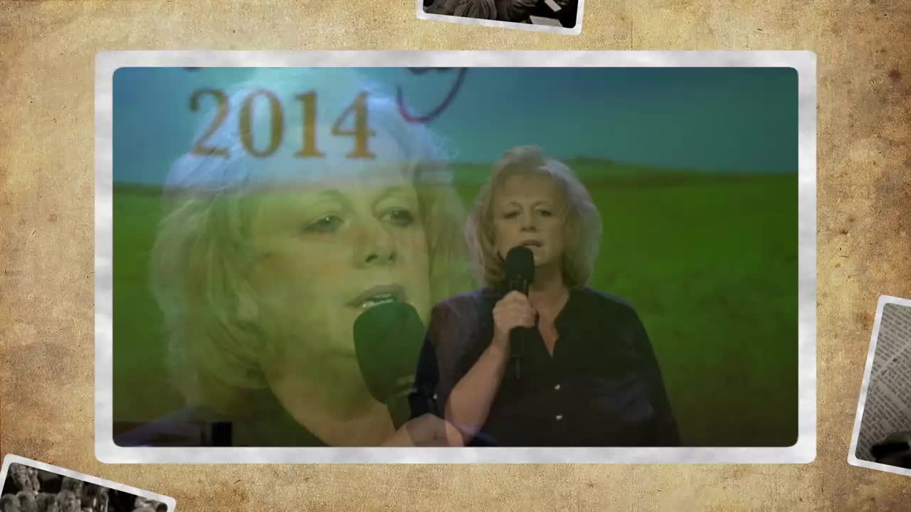 A woman with blonde hair holds a microphone and speaks into it. Behind her, the year "2014" is superimposed over a faint image of her face.
