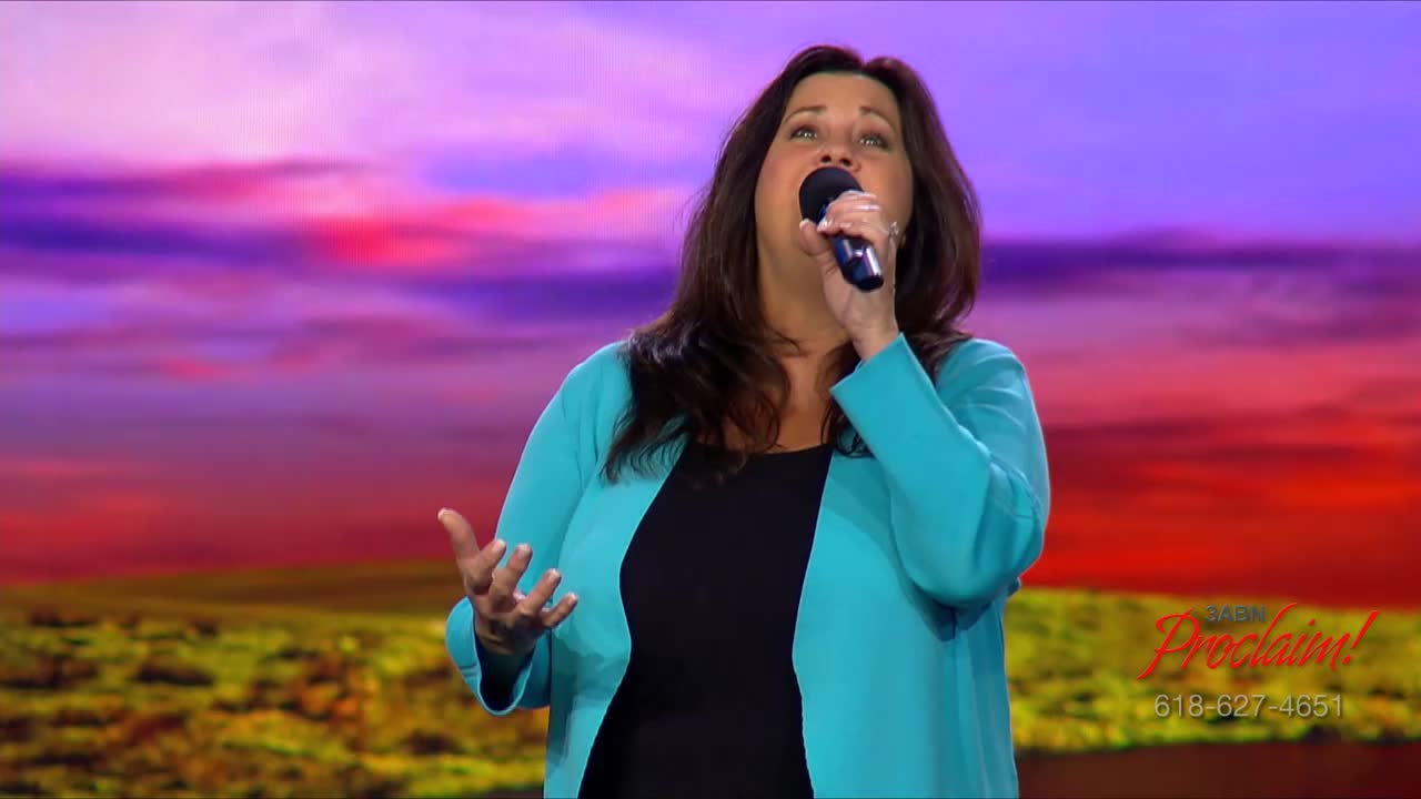 A woman, microphone in hand, sings with her eyes closed, her hands gesturing. The 3ABN Proclaim! Network logo is visible in the lower right corner.
