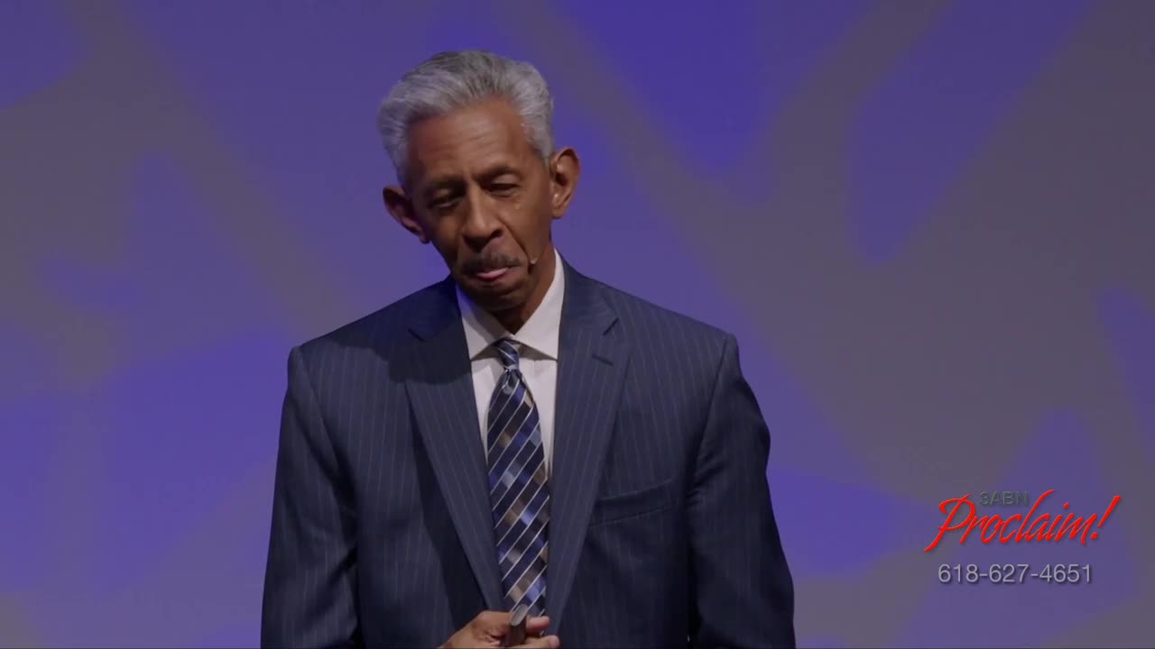 A man in a suit stands on a stage, looking down with a slight frown. The 3ABN Proclaim! Network logo is visible in the corner.
