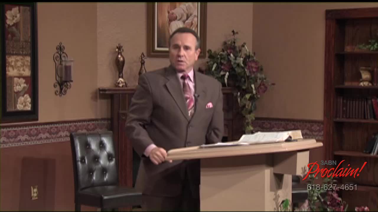 A man in a brown suit stands at a wooden podium, speaking into a microphone. The 3ABN Proclaim! Network logo is visible on the right.
