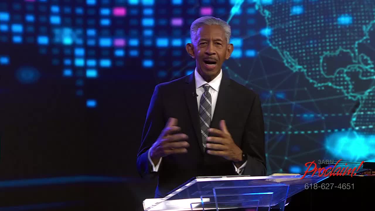 A man in a suit stands at a podium, gesturing with his hands while speaking. Behind him, a digital map and the 3ABN Proclaim! Network logo are visible.
