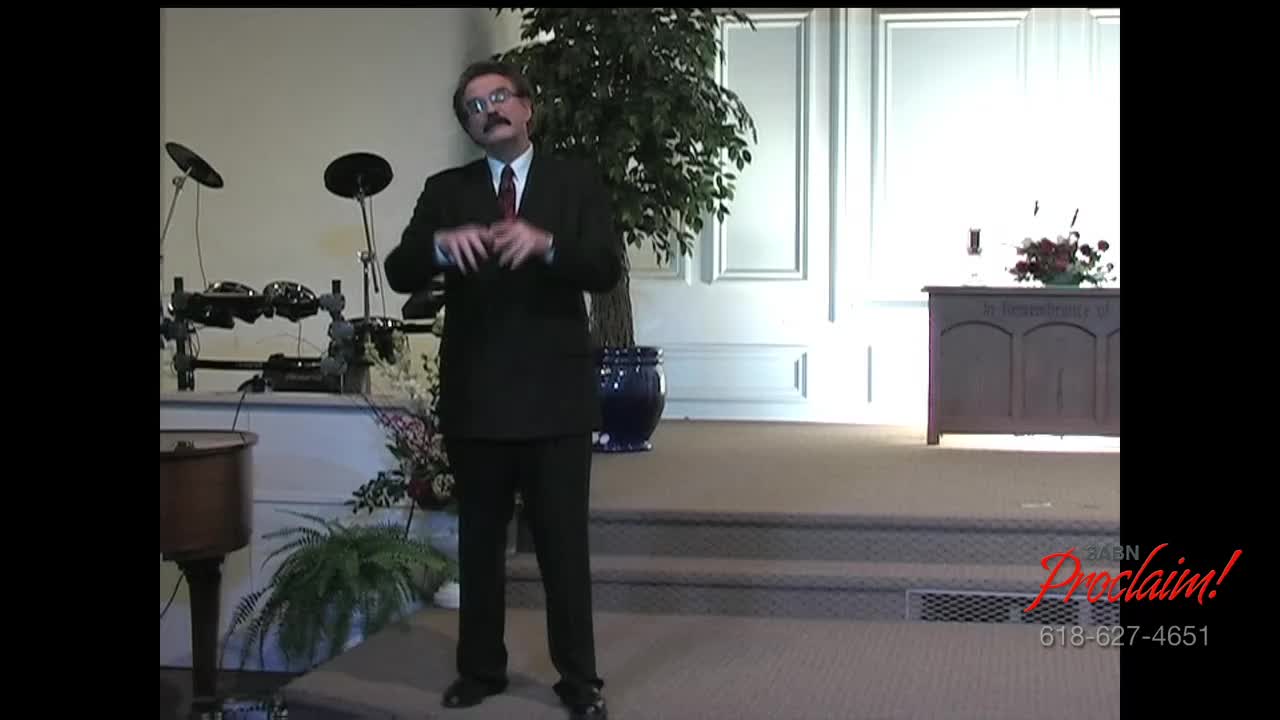 A man in a dark suit gestures with his hands as he speaks on a stage. The 3ABN Proclaim! Network logo is visible in the lower right corner.
