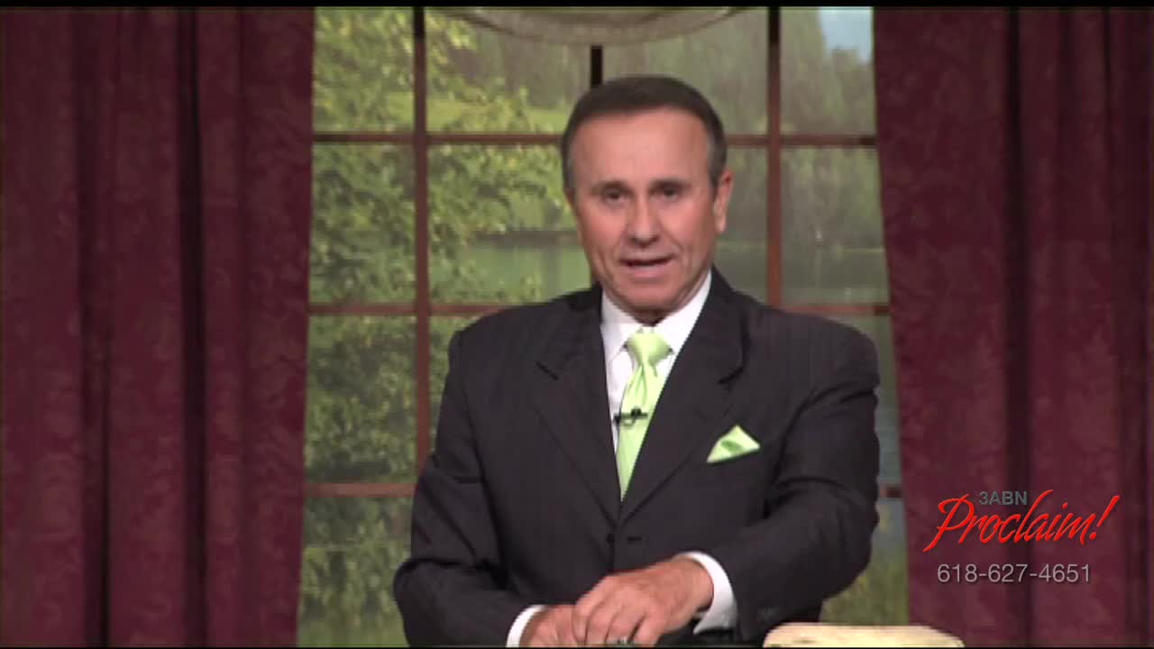 A man in a dark suit and lime green tie speaks directly to the camera, likely on the 3ABN Proclaim! Network. Behind him, a window reveals a blurry, green outdoor scene.

