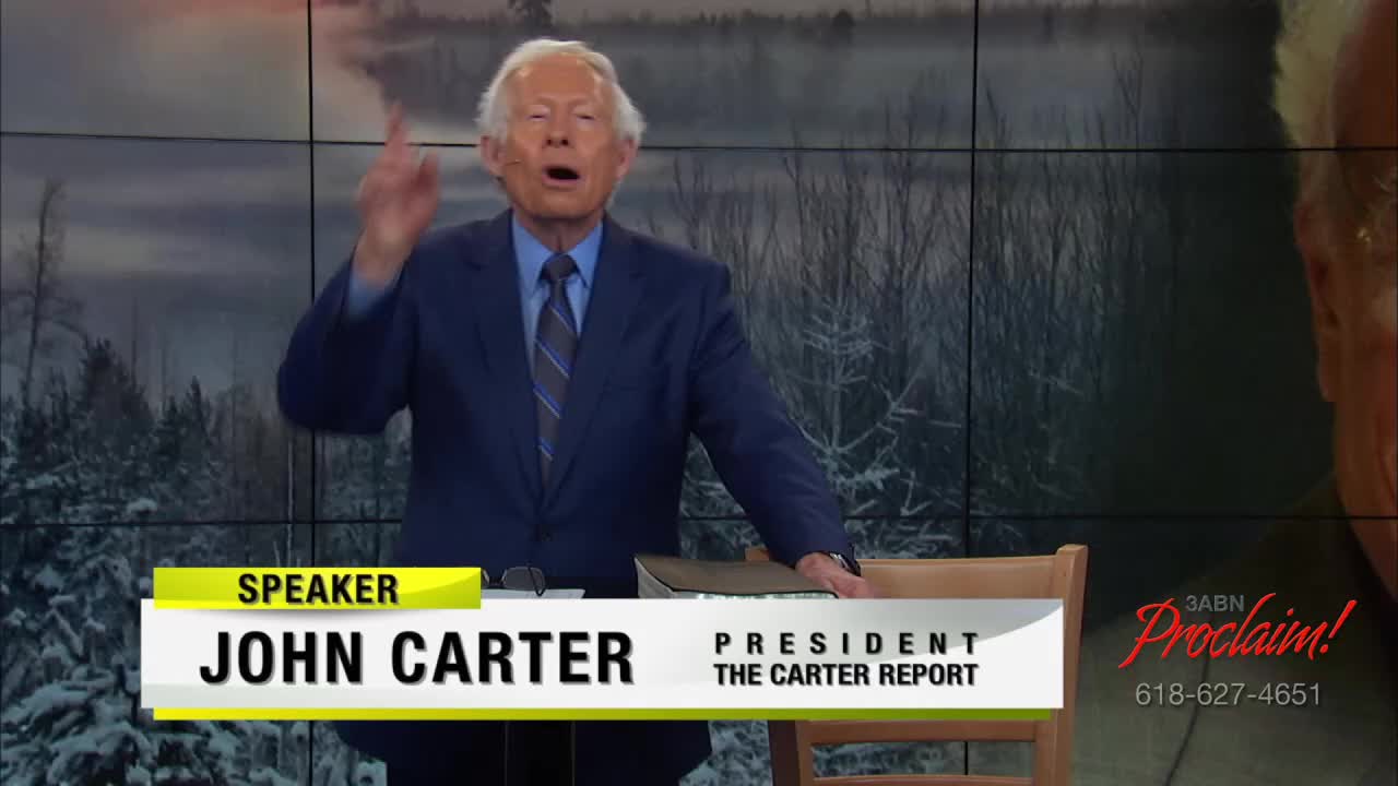John Carter, in a blue suit, gestures emphatically with his right hand while speaking on the 3ABN Proclaim! Network. The backdrop features a wintry landscape.
