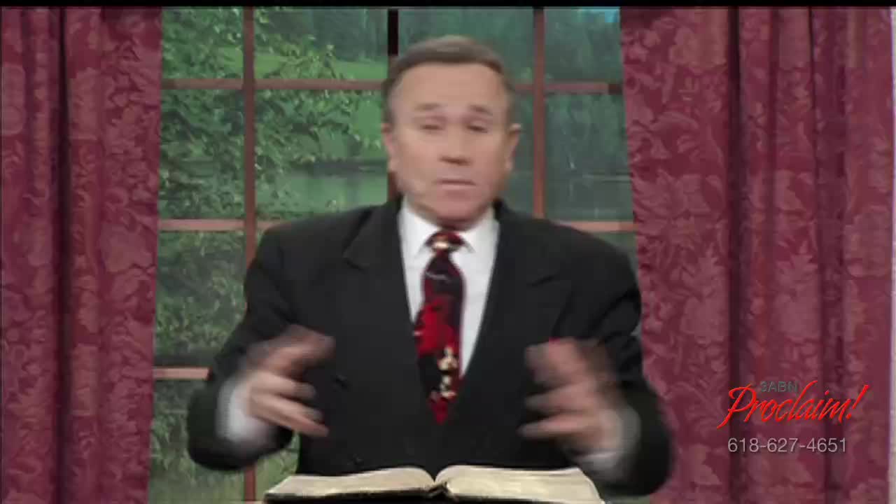 A man in a suit gestures with his hands, speaking from behind an open book. The 3ABN Proclaim! Network logo is visible in the corner, likely broadcasting from the United States.
