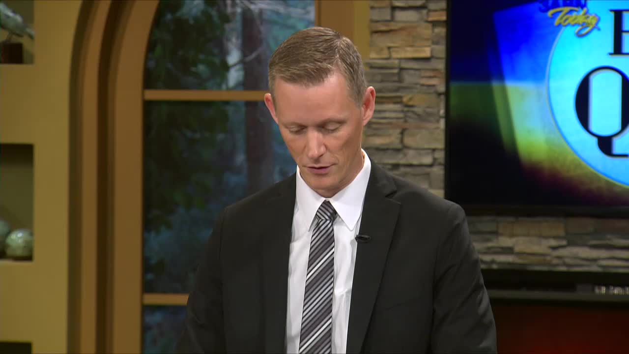 The man in the suit stands at a desk, looking down.  Behind him, a screen displays "Today's Big Question" from the 3ABN Proclaim! Network in the United States.
