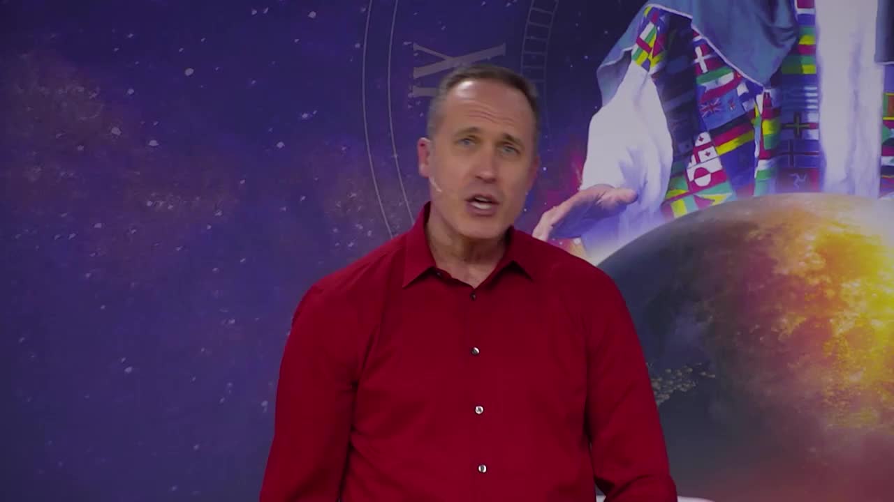 The man in the red shirt is speaking, his mouth open as if mid-sentence. Behind him, a celestial backdrop includes a globe and a figure draped in white and colorful fabrics.
