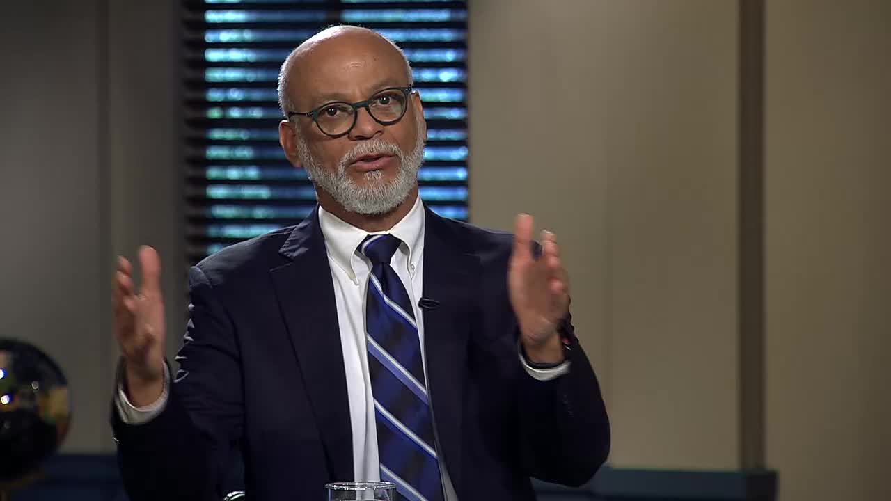 A man in a navy suit and tie gestures with both hands as he speaks. He's on the 3ABN Proclaim! Network, likely in the United States, and appears to be making a point.
