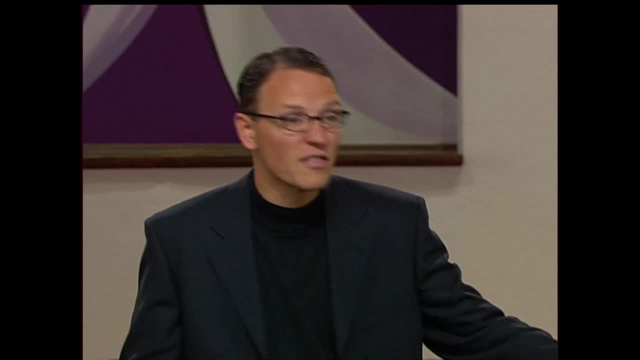 A man in a dark suit and turtleneck speaks with conviction. He's on a set for the 3ABN Proclaim! Network, likely in the United States.