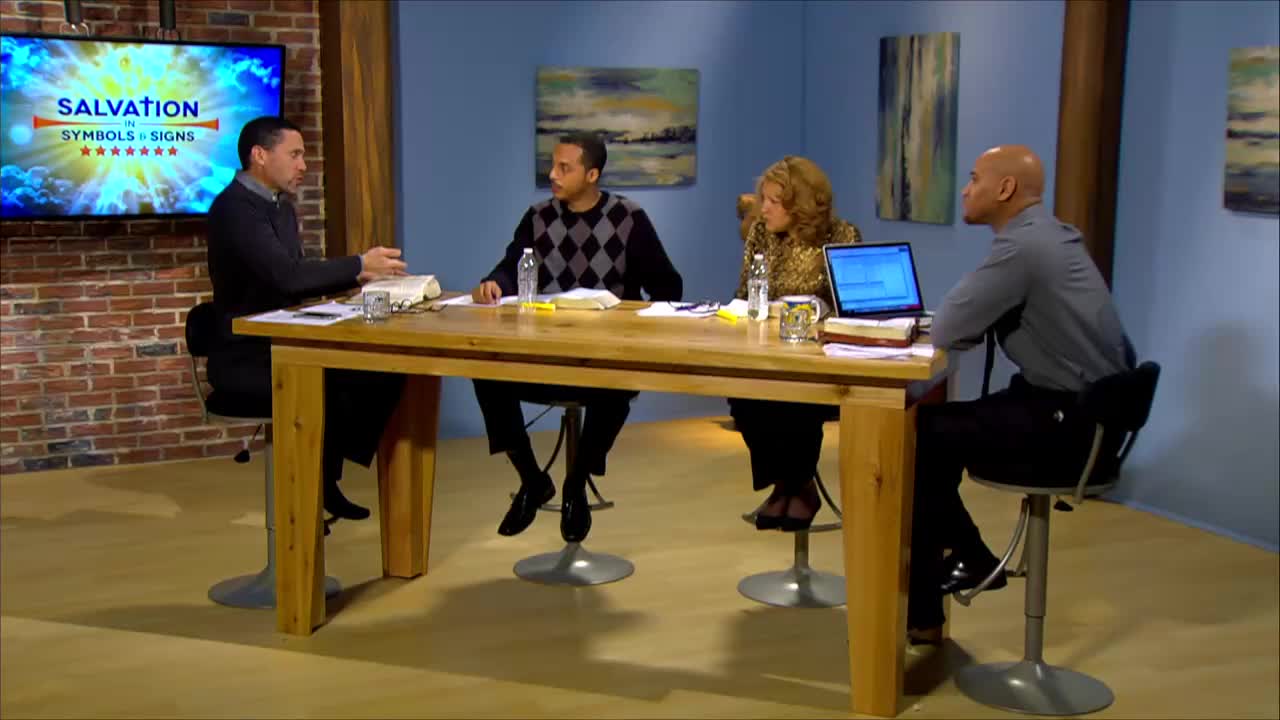 A panel of four people sits around a wooden table, discussing biblical topics for the 3ABN Proclaim! Network. A large screen behind them displays the program title, "Salvation: Symbols & Signs."