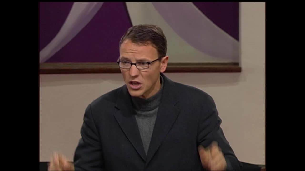 A man in a suit and turtleneck gestures animatedly while speaking. He's on a set that looks like it's for a broadcast, perhaps for the 3ABN Proclaim! Network.