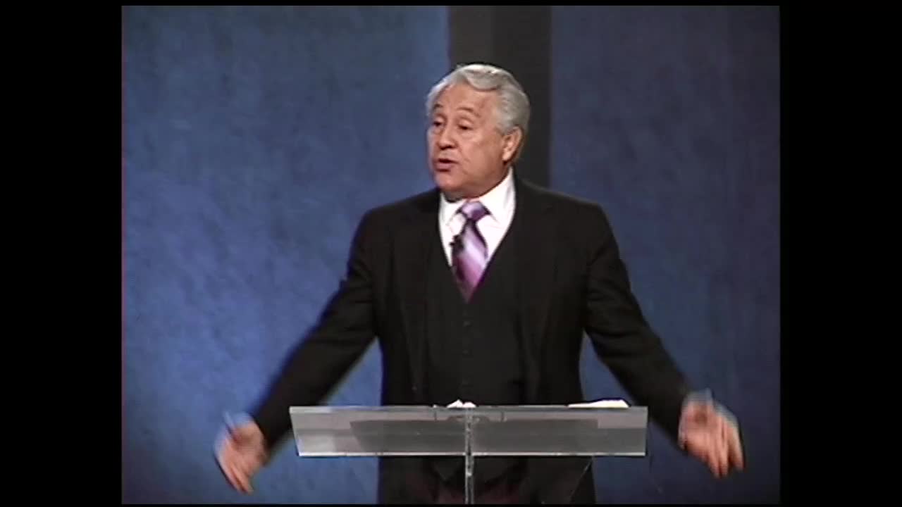 A man in a suit and tie stands behind a clear podium, speaking with his hands gesturing outward. He's on a stage, likely broadcasting for the 3ABN Proclaim! Network.