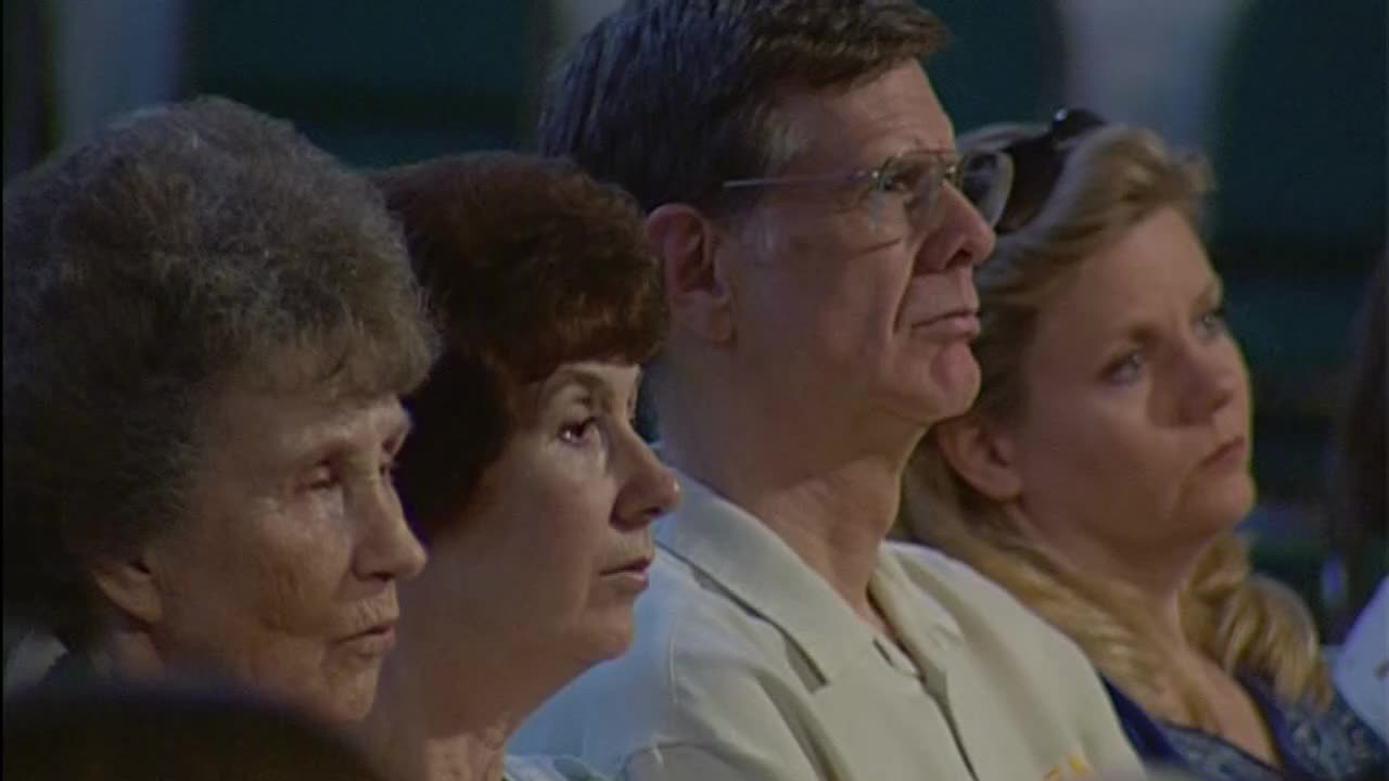 People are seated, their faces turned upward, listening intently. The 3ABN Proclaim! Network broadcast plays before them.