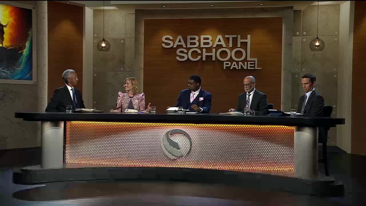 Five people sit behind a desk, bathed in warm light. The "Sabbath School Panel" is displayed prominently behind them.