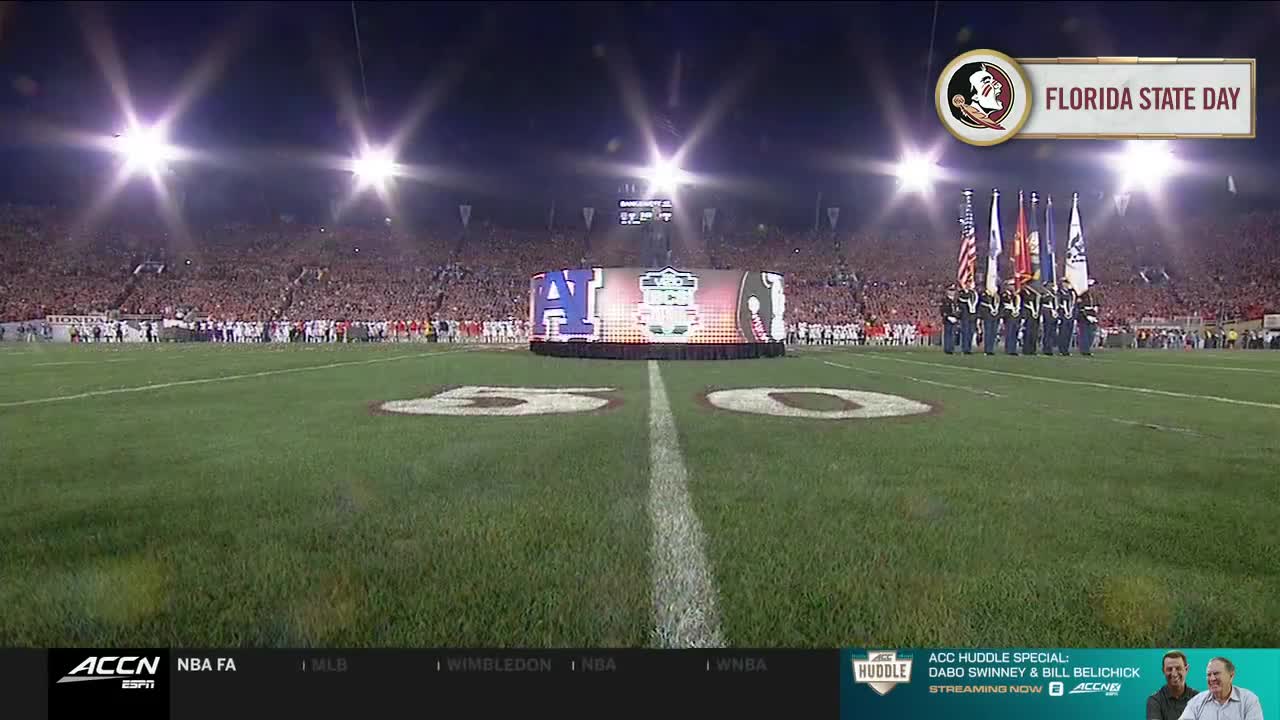 The crowd is packed, and a color guard stands at attention on the field. The ACC Network is broadcasting "Florida State Day" from the stadium, with a large video screen at midfield.
