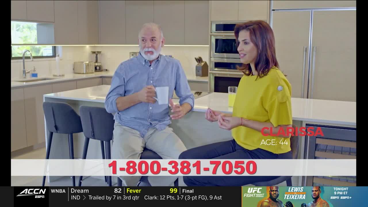 A woman in a yellow shirt gestures while speaking to a man holding a mug across a kitchen island. Below, an ACC Network graphic advertises a phone number and a UFC fight.
