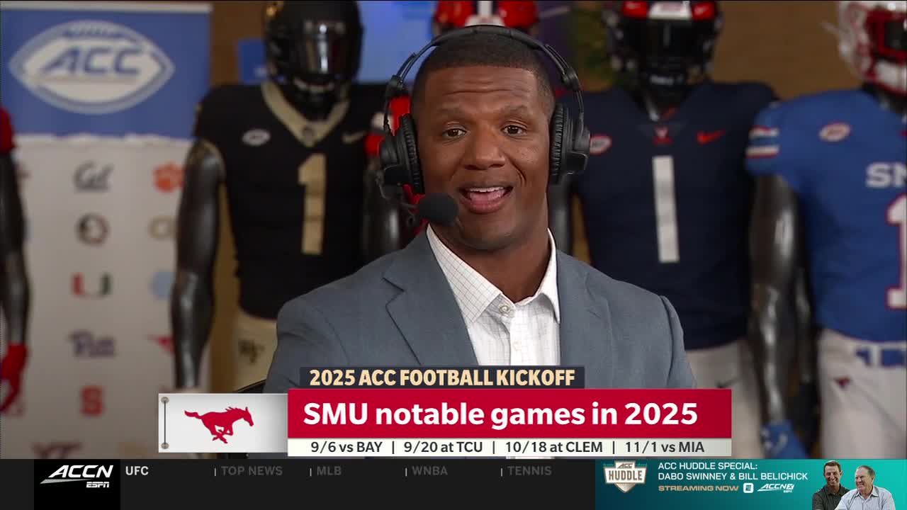 A man in a suit and headset is speaking, with the ACC Network logo visible in the background. Behind him, football uniforms on mannequins are displayed.
