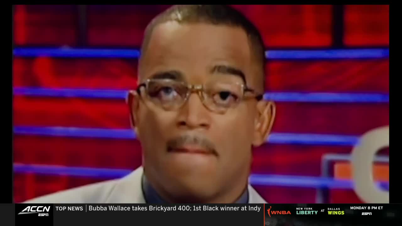 A man in glasses and a light-colored jacket looks directly at the camera, his expression serious. The ACC Network logo and a news ticker are visible at the bottom of the screen.
