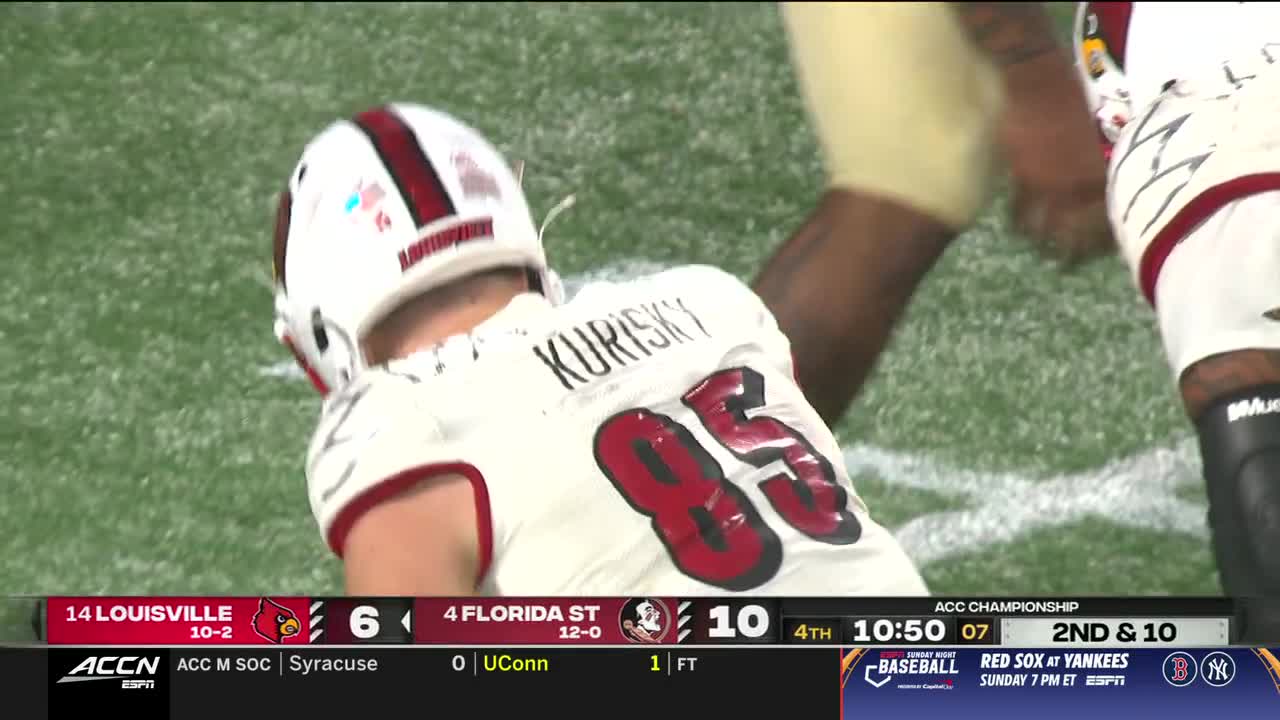 A player in a white and maroon jersey is down on the field, the number 85 visible on his back. The ACC Championship game is underway, with Florida State leading Louisville.
