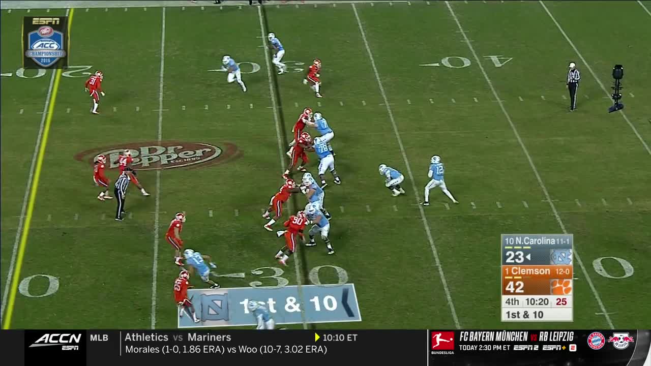 Clemson's offense, in orange, is lined up against North Carolina's defense, in blue. The quarterback, in blue, is dropping back, and the play is underway.

