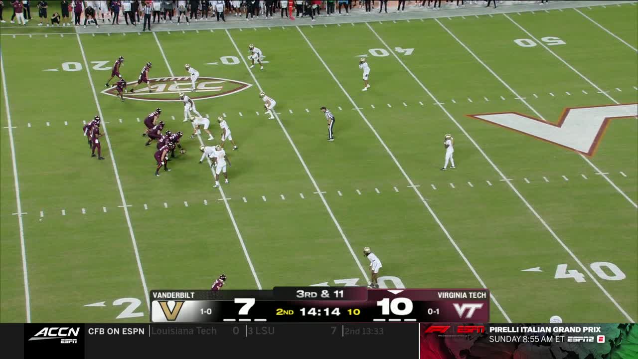 The Vanderbilt offense, in their maroon and gold, lines up against Virginia Tech's white jerseys. The play clock ticks down as the quarterback surveys the field on this ACC Network broadcast.
