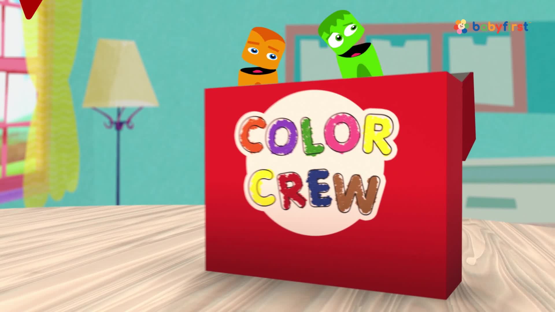 Two puppet-like characters, one orange and one green, peek over the top of a red box. The box is labeled "Color Crew" and sits on a table in what looks like a BabyFirst set.
