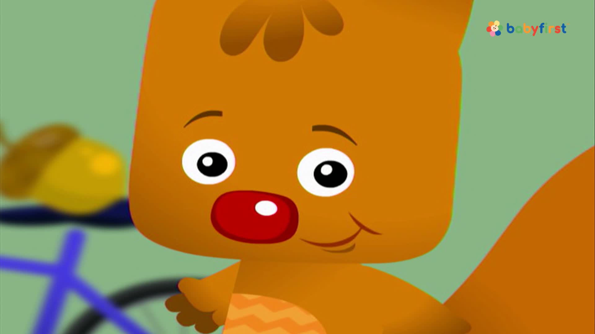 A cartoon squirrel with a red nose and big eyes looks directly at me. Behind him, a bicycle and an acorn are slightly out of focus.
