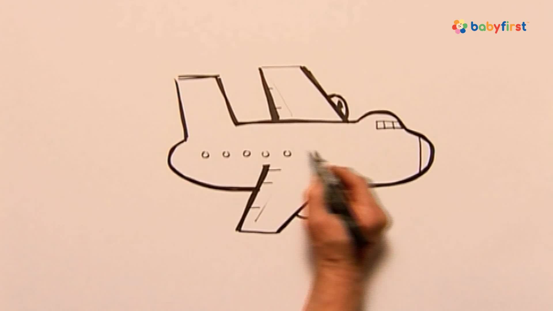 A hand, holding a black marker, is drawing the outline of an airplane on a white surface. The drawing is simple, with the plane's body, wings, and windows already sketched.
