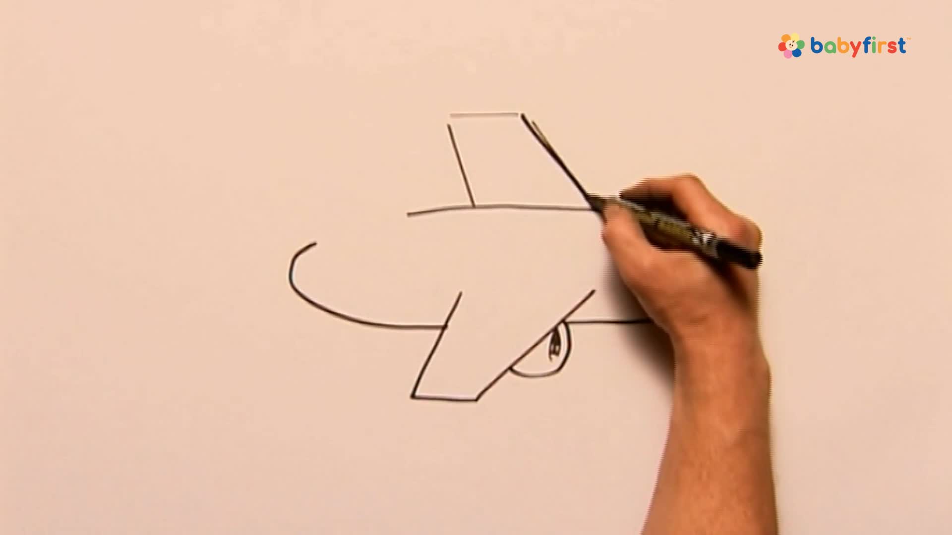 A hand with a pen is sketching the tail of a cartoon airplane on a white surface. The drawing is simple, with thick black lines.
