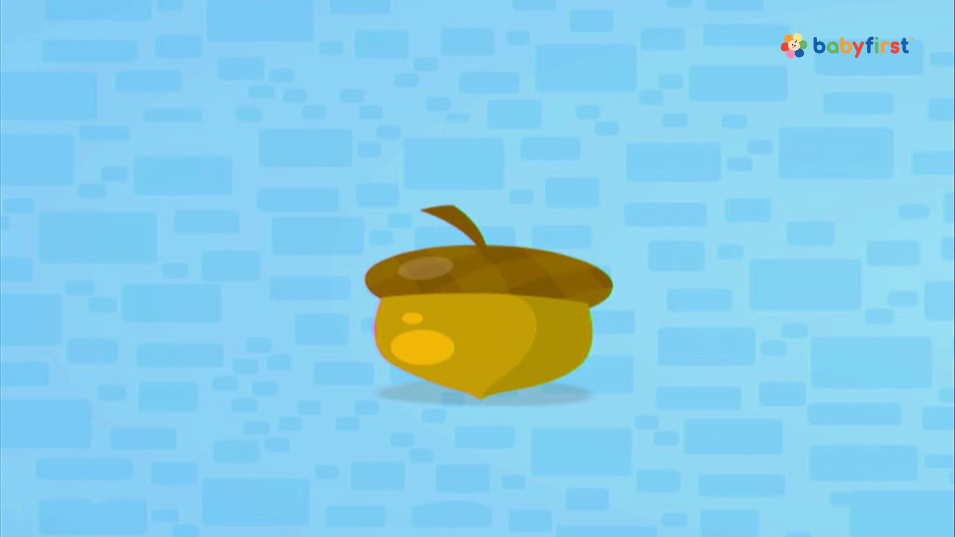 A cartoon acorn, with a brown cap and a yellow body, sits centered against a blue, blocky background. The BabyFirst logo is visible in the upper right corner.
