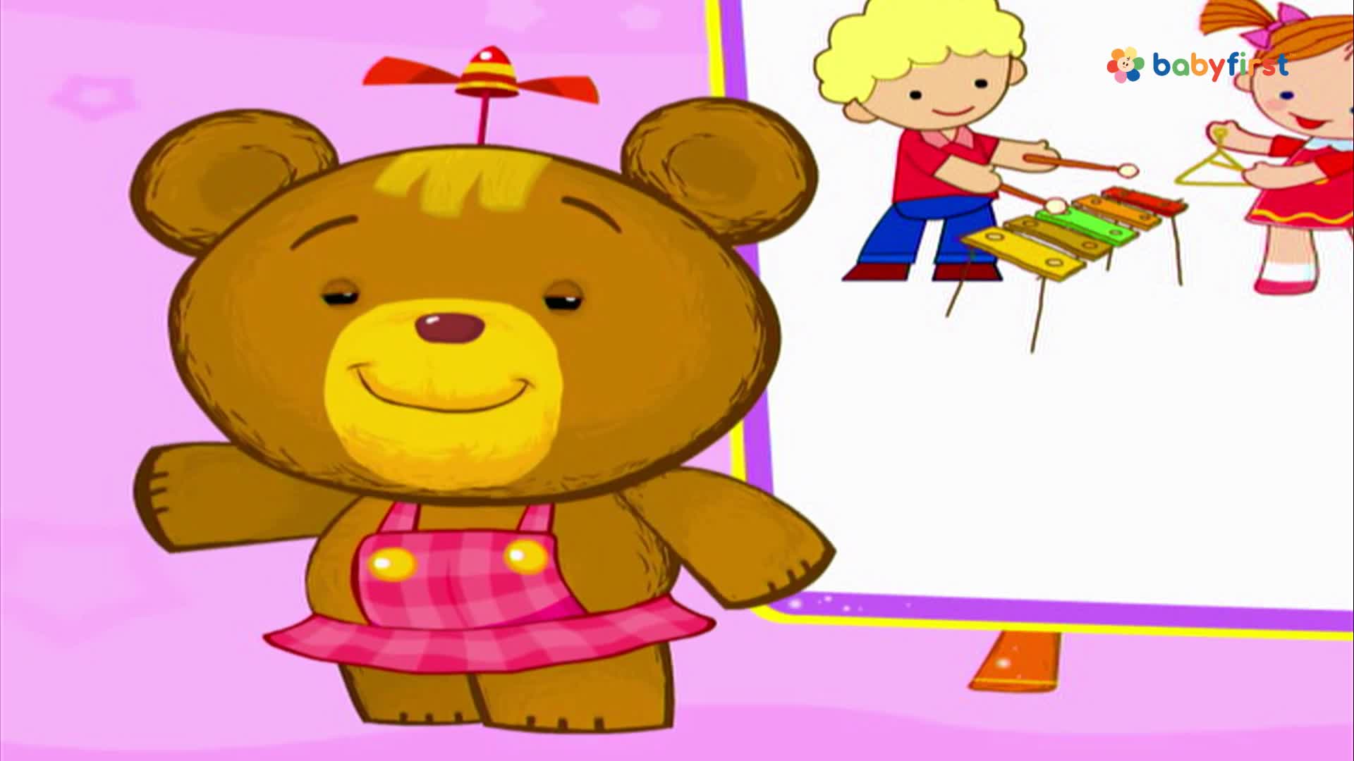 A smiling bear with a propeller on its head stands in front of a screen. On the screen, two cartoon children play musical instruments, a xylophone and a triangle.
