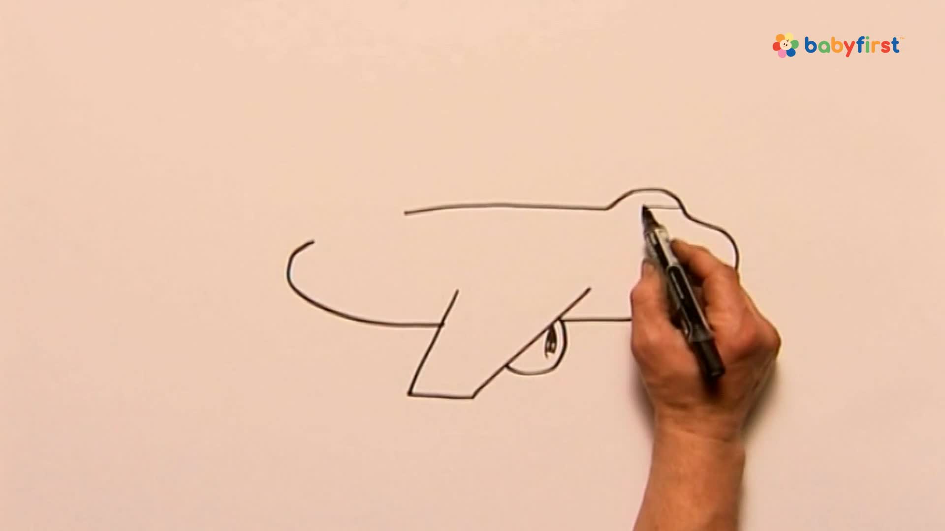 A hand holds a black marker, adding a rounded top to the outline of an airplane. The drawing is simple, with a wing and a large eye already sketched.
