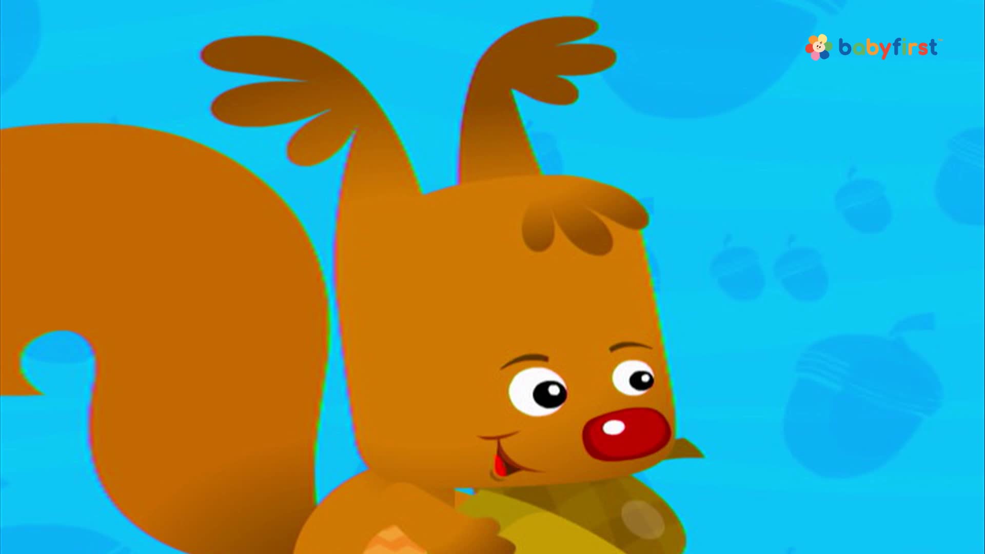 A cartoon squirrel holds a large nut, its red nose and wide eyes visible. The background is a bright blue with acorns, and the BabyFirst logo is in the corner.
