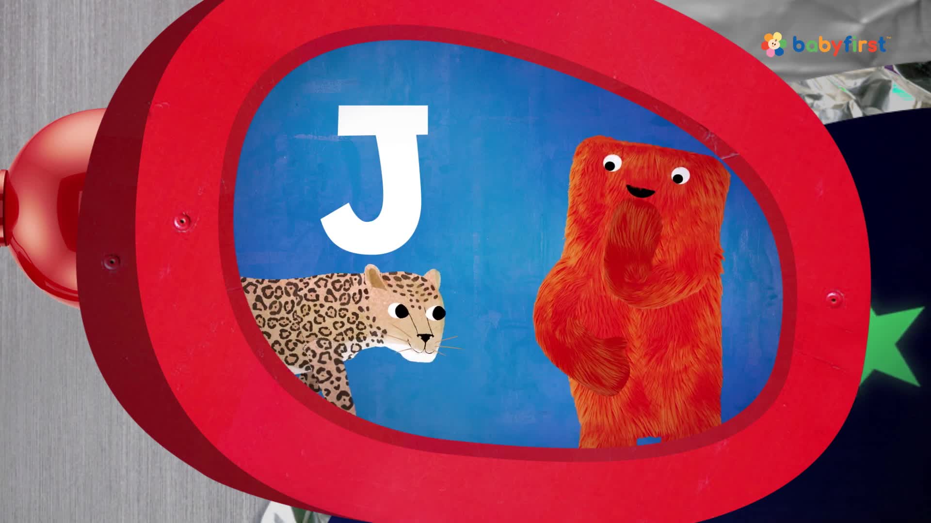 A cartoon leopard and a fuzzy orange character stand inside a red-framed circle. The letter "J" is displayed above them against a blue backdrop, likely from a BabyFirst program.
