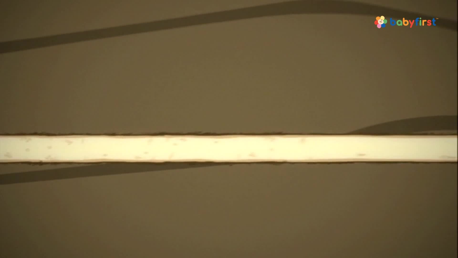 A bright, rectangular shape glows against a muted brown background. The BabyFirst logo is in the upper right corner.
