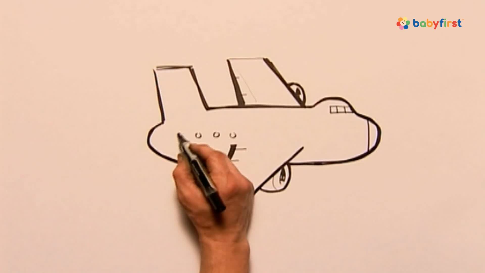 A hand is drawing a simple airplane with a black marker on a white surface. The artist is adding small circles to the side of the plane's body.
