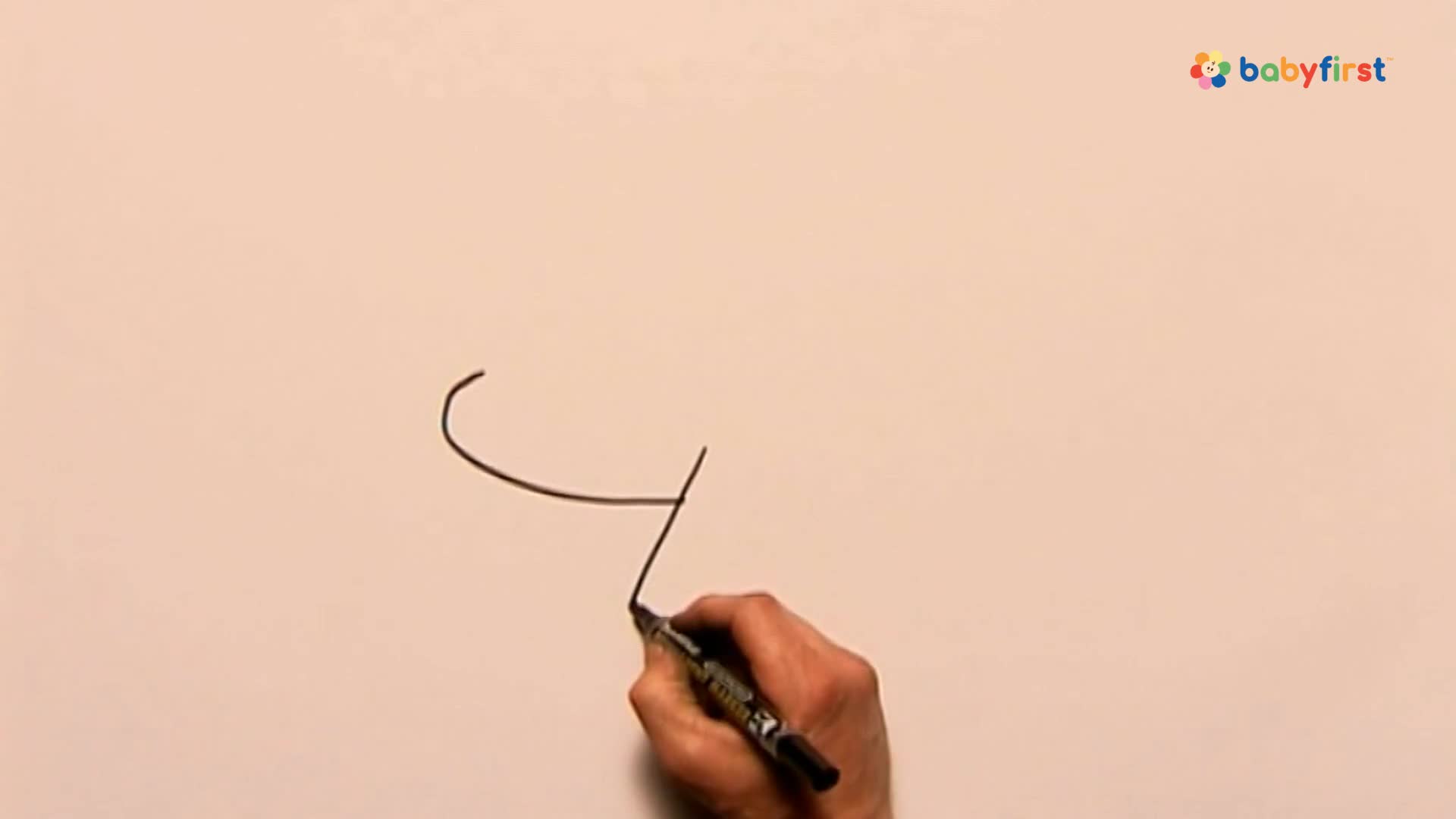 A hand holds a black marker, drawing a curved line followed by a straight one. The lines are forming a simple shape against a pale background.
