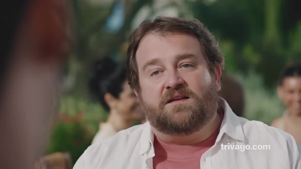 A man with a beard and a white shirt is talking, his mouth slightly open. The trivago.com logo is visible in the bottom right corner.
