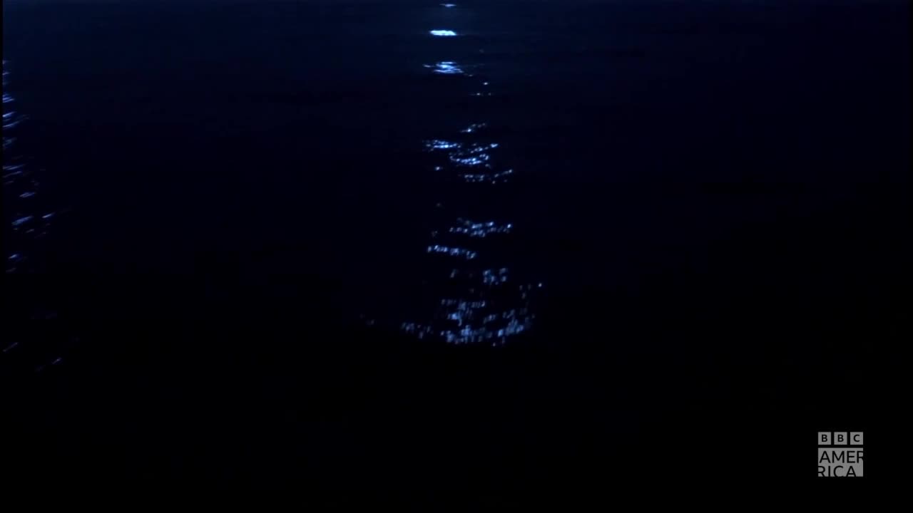 A shimmering path of light stretches across the dark water. The BBC America logo sits in the bottom right corner.
