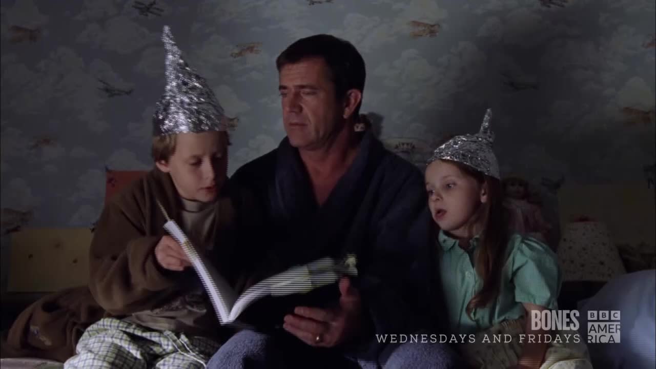 A man in a robe reads a book to two children, all wearing foil hats. The BBC America logo is visible, and it looks like a scene from "Bones."
