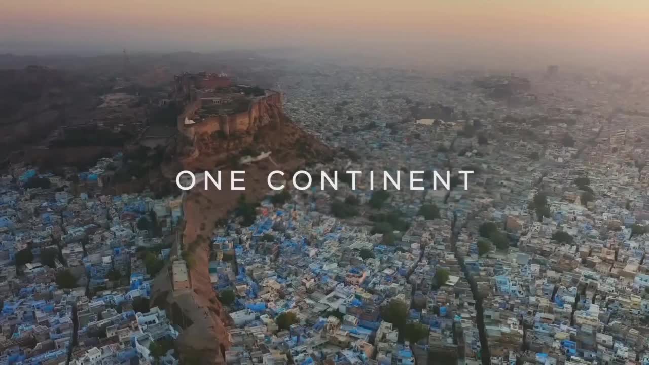 The BBC America logo is nowhere to be seen, but the scene is a wide shot of a city, mostly blue buildings, under a hazy sky. A large fortress sits atop a hill, and the words "ONE CONTINENT" are centered in the frame.
