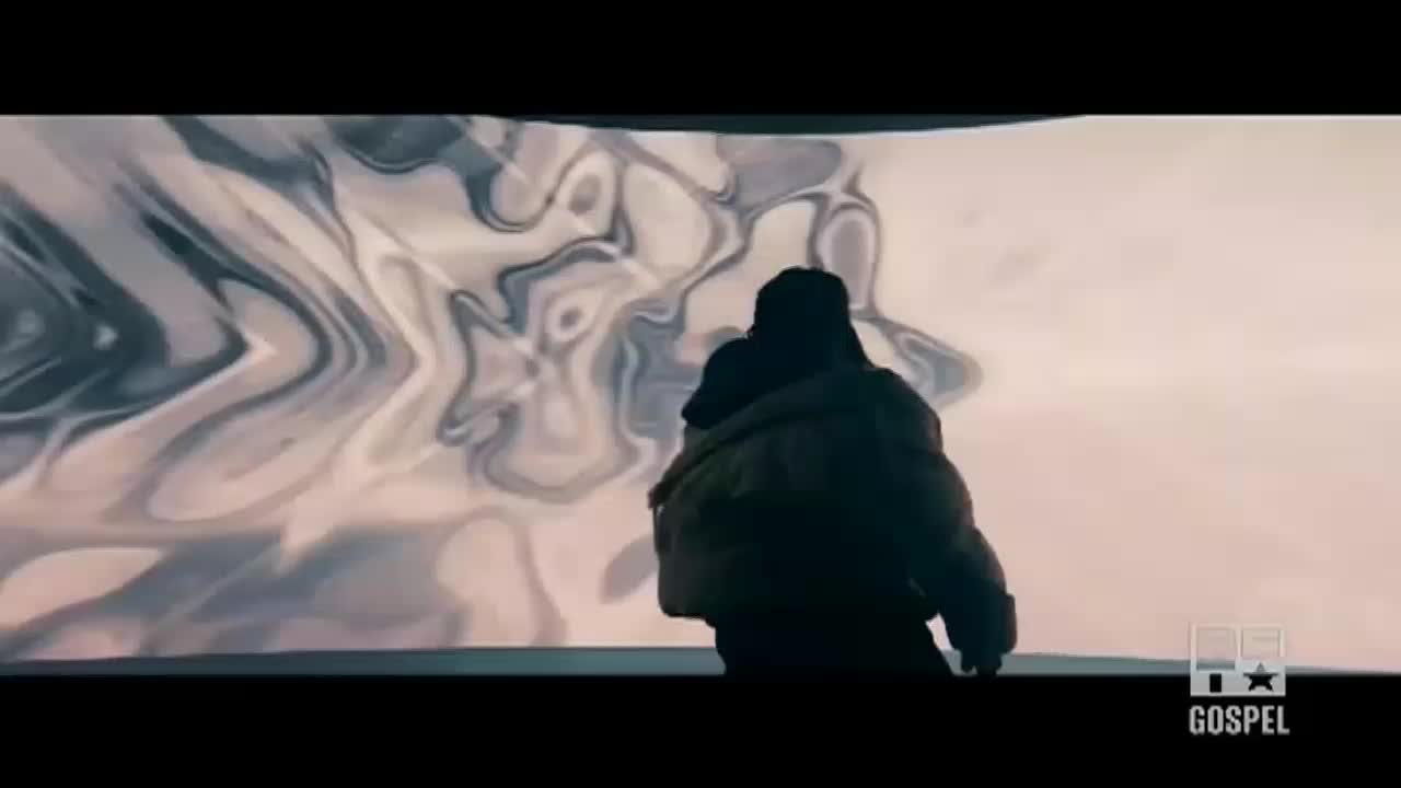 A person in a dark coat stands facing a wall of swirling, liquid-like patterns. The BET Gospel logo is visible in the corner.
