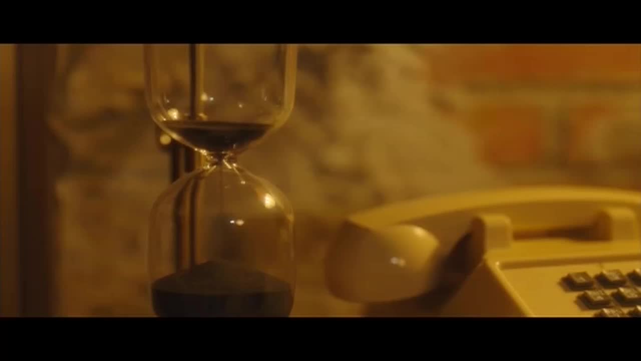 The dark sand is falling slowly through the hourglass, a yellow rotary phone sits nearby. The scene is lit with a warm, golden light.
