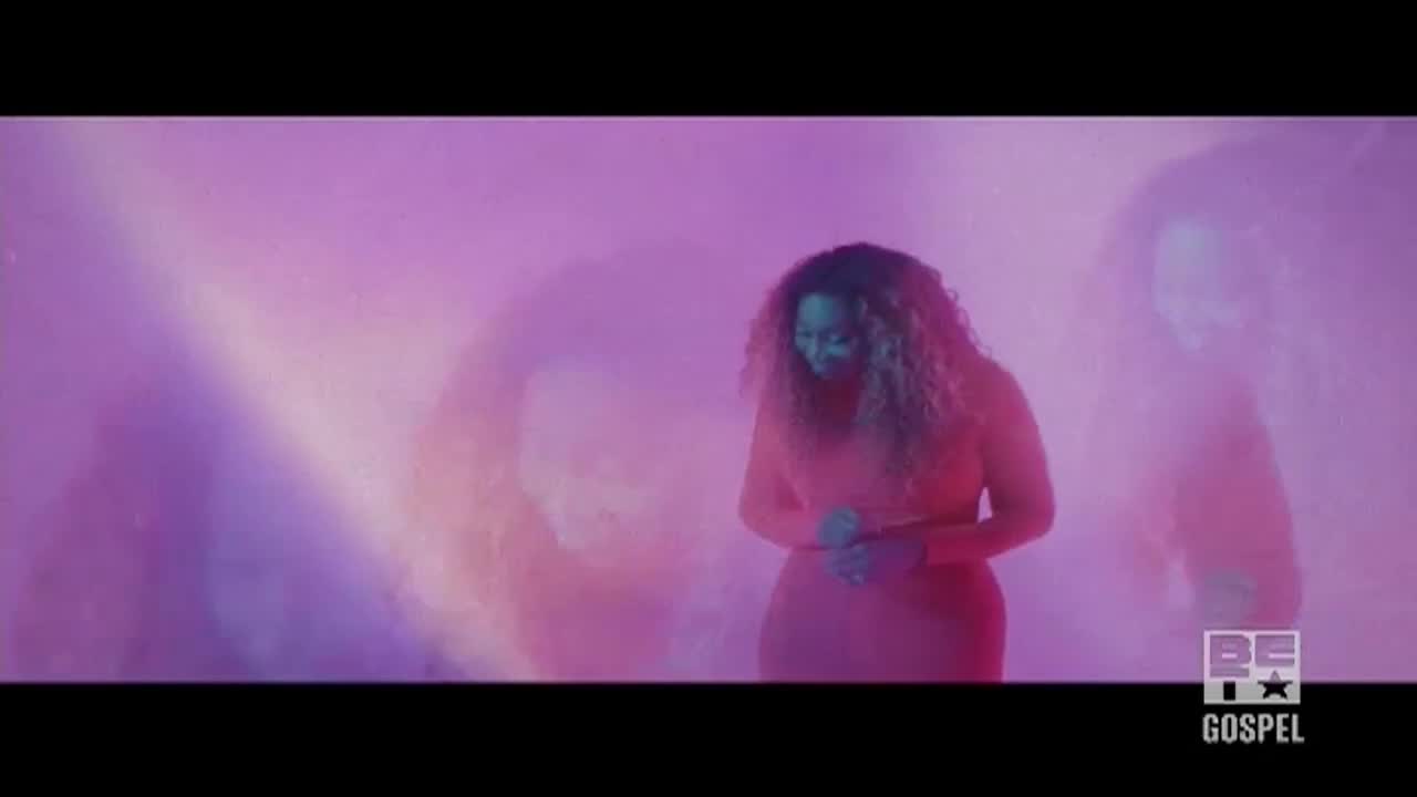 A woman in a red outfit stands in front of a purple backdrop, her hands clasped. The BET Gospel logo is visible in the corner.
