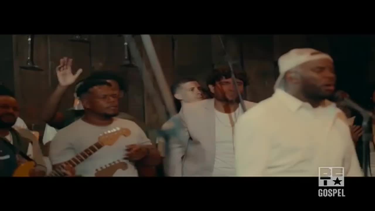 A man in a white cap sings into a microphone as a band plays behind him. The BET Gospel logo is visible in the corner.
