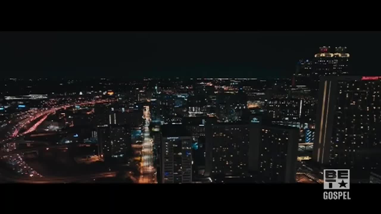 The city sprawls out below, a web of lights against the dark sky. Headlights stream along the highways, and the BET Gospel logo sits in the corner.
