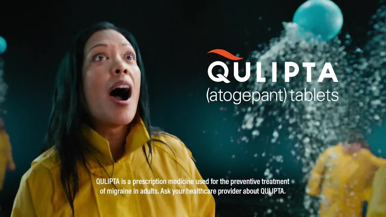 A woman in a yellow raincoat stares upward with her mouth open, as a cloud of white bursts around her. The QULIPTA logo is prominently displayed, with a tagline about migraine treatment.

