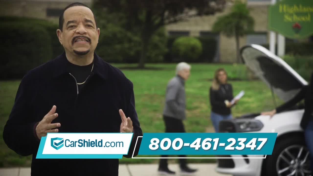 Ice-T gestures with his hands in front of a green lawn, while a car with its hood up sits nearby. A CarShield.com logo and phone number are displayed on the screen.
