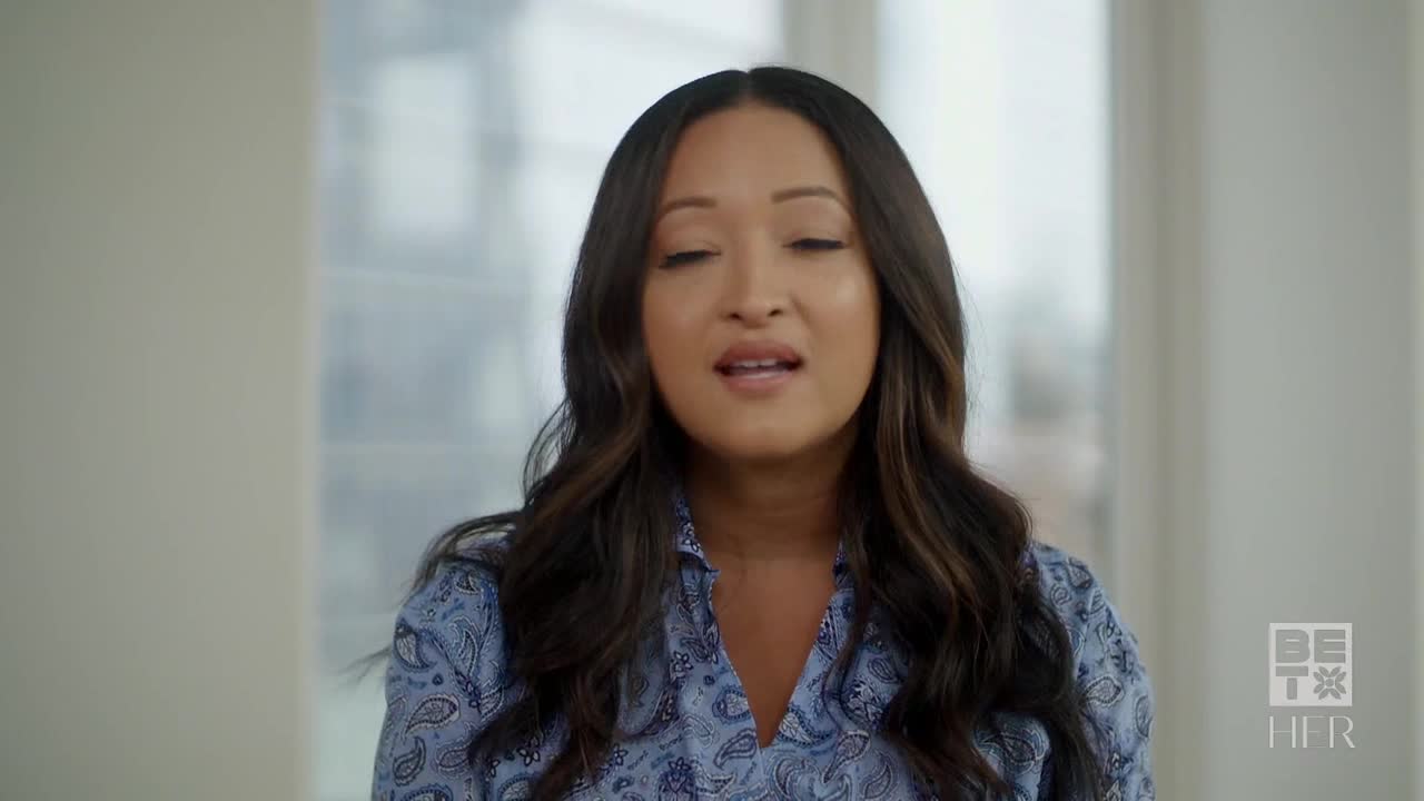 A woman with long, wavy hair is speaking, her mouth open as she forms words. She's wearing a blue patterned shirt, and the BET Her logo is visible in the corner.
